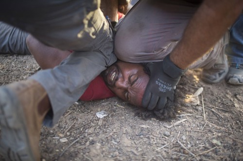 Israeli policemen and immigration officers arrest an African asylum seeker after spending the last t