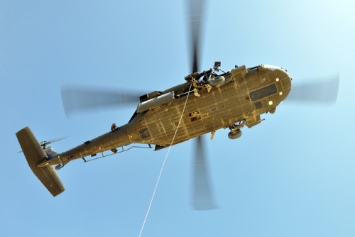 An Army National Guard UH-60 Blackhawk helicopter crew prepares to hoist Air Force pararescuemen fro