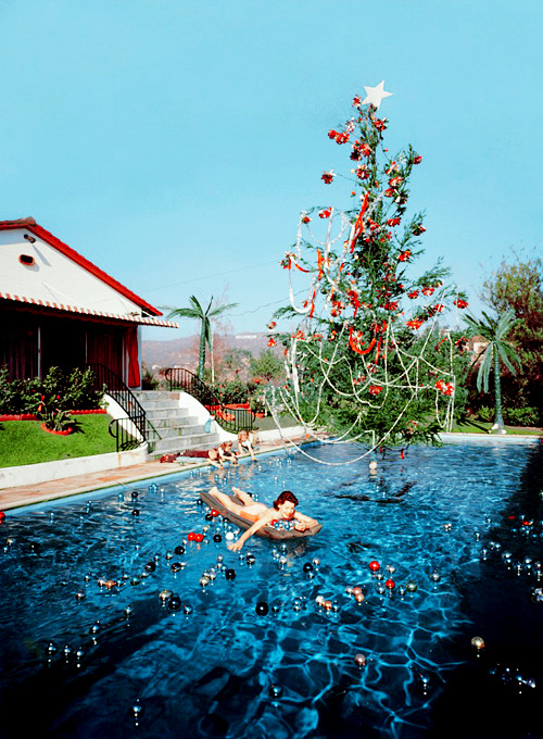  Rita Aarons, wife of photographer Slim Aarons, swimming in a pool festooned with floating baubles and a decorated Christmas tree, Hollywood, California, 1954.(via) 