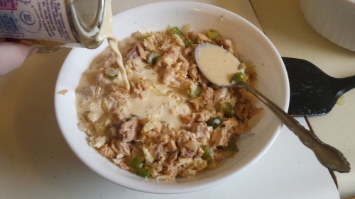 a can of evaporated milk being added to the bowl of bread crumbs, onions, and green peppers