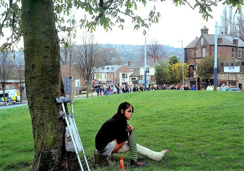 Somewhere in England a girl with a well worn long leg cast rests under a tree after shopping as foot