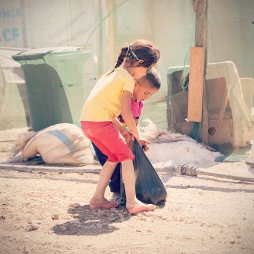 Two Syrian refugee kids in Lebanon struggle to carry home a food pack supplied by Open Doors partner