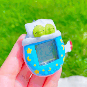 A customized Tamagotchi that resembles blue sheets on a bed. Under the covers are two Kuchipatchi.