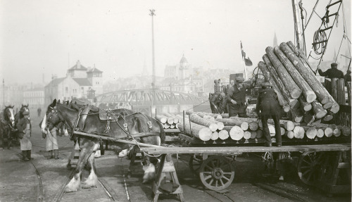 A scene from a Danish port about 1910-20s. A pile of trunks is being unloaded on a waggon. Hard to s