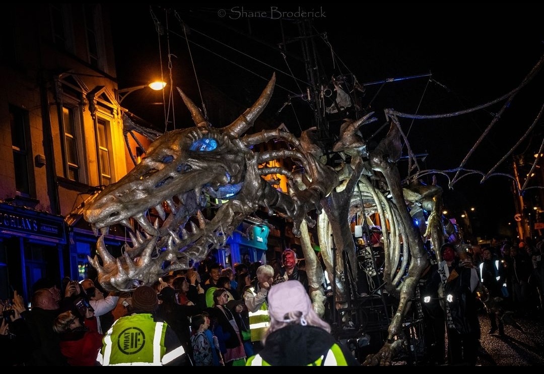 photo of a giant skeletal dragon puppet in a parade in a city at night