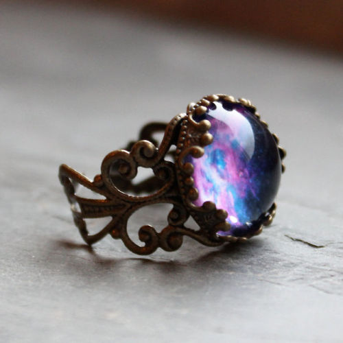 wickedclothes:  Adjustable Violet Nebula Ring A glass dome rests on this fully adjustable, antique brass ring. Inside of the dome is a vibrant picture of a violet-colored nebula. An accessory that your friends will surely say is “out of this world.”