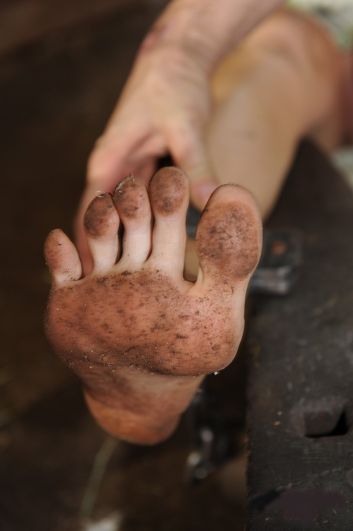 A bare female foot in process of being shackled. The girl was probably marched barefoot all the way 