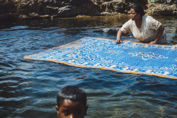 brassmanticore: A Nubian woman cleaning her carpet in the Nile while her child is having a swim. Nour el Rifai 