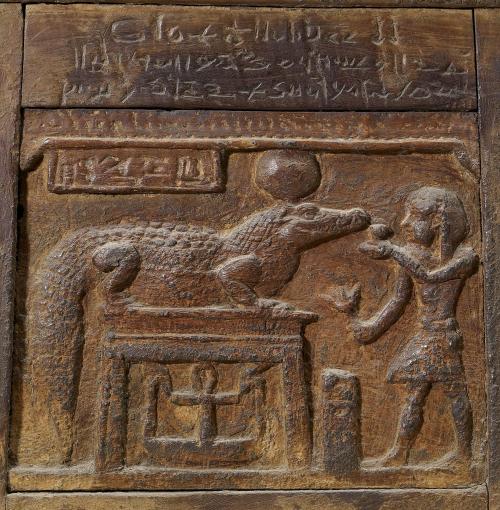 Detail of an ancient Egyptian wooden chest, showing a king making an offering to the crocodile-god S