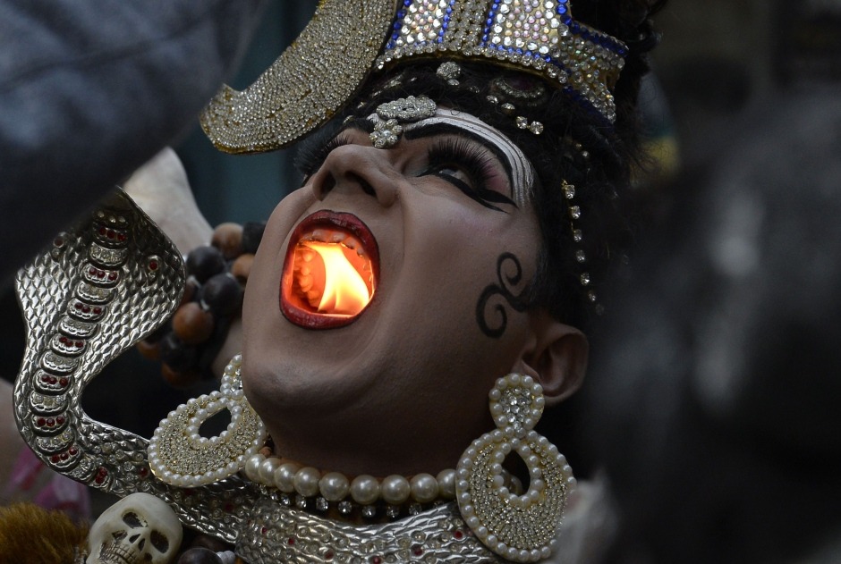 sixpenceee:   A Hindu man dressed as Lord Shiva holds a lit  candle in his mouth