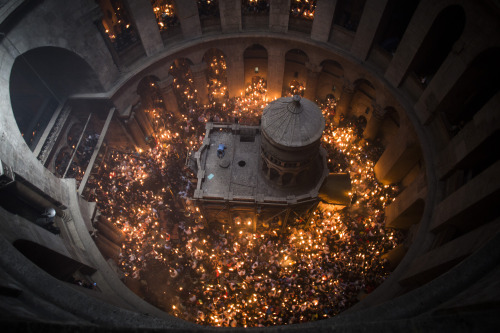A man seen lying and praying on top of the tomb of Jesus Christ, as thousands of Orthodox Christian 