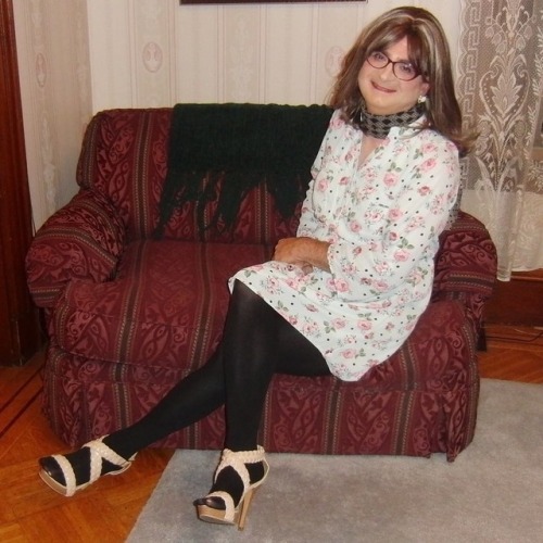 Full-length picture of me, seated, knees right, legs crossed, wearing my new purple cat-eye glasses,