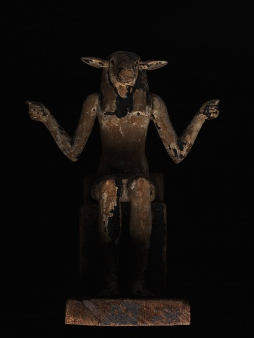 virtual-artifacts:Wooden figure of an enthroned ram-headed god with arms outstretched; overlaid with