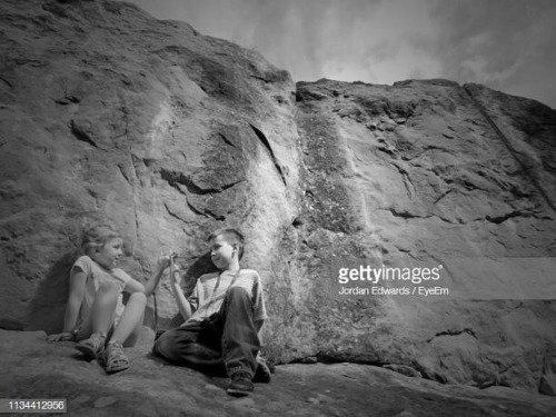 Siblings Playing Against Rock Formation caption - Photo taken in...