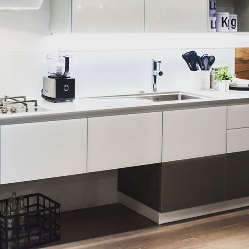 Classic modern kitchen design with white and black features a soft white glass backsplash. Sort of a