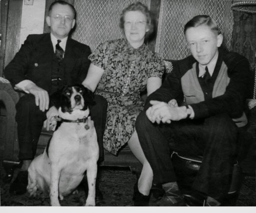 Carl, Dena and Charles Schulz sit on a sofa with their dog Spike in the foreground, circa 1937. Char