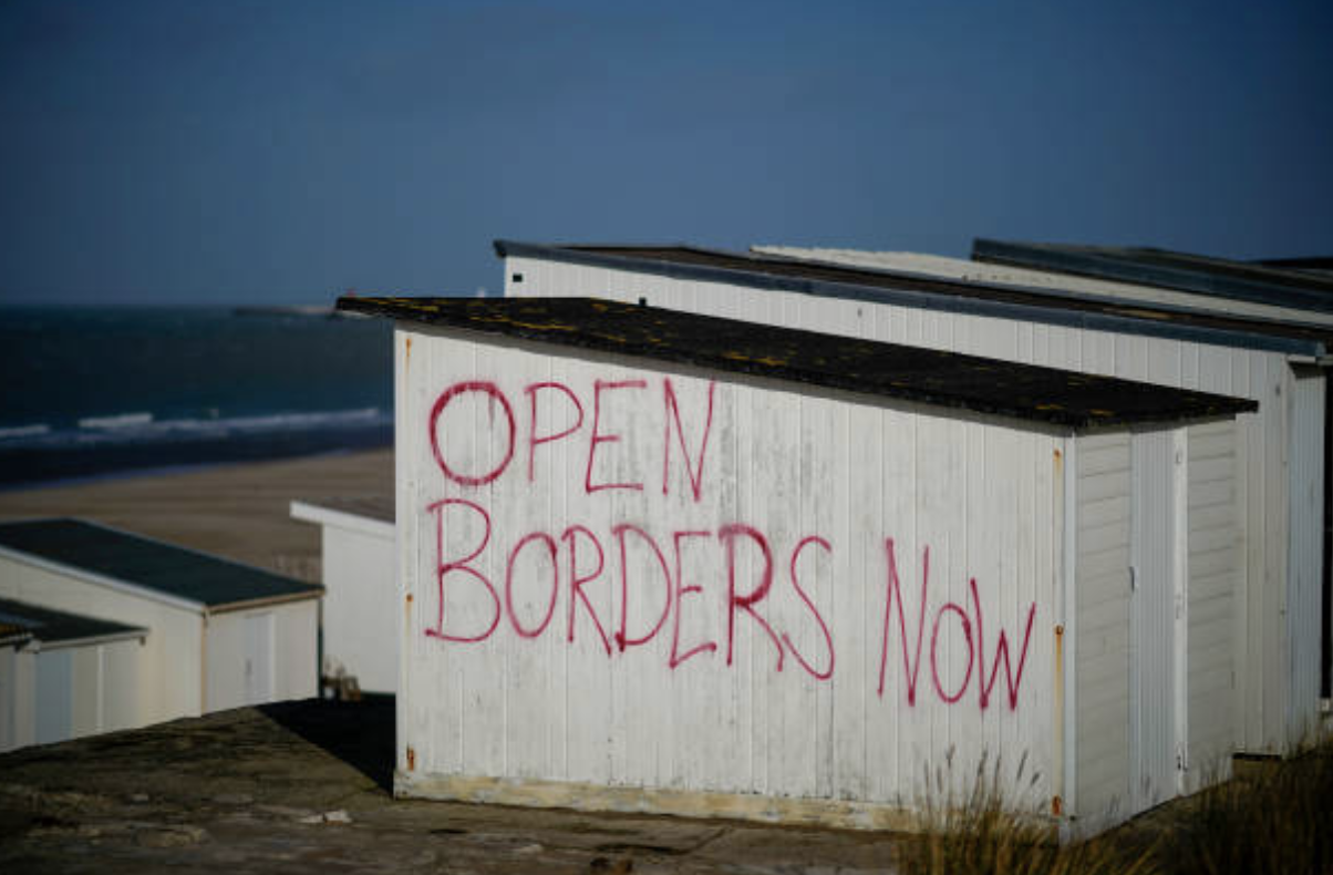 Graffiti reading &ldquo;OPEN BORDERS NOW&rdquo; on a beach hut near the Calais Ferry terminal on Feb