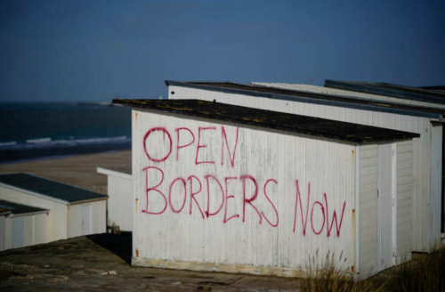 Graffiti reading “OPEN BORDERS NOW” on a beach hut near the Calais Ferry terminal on Feb