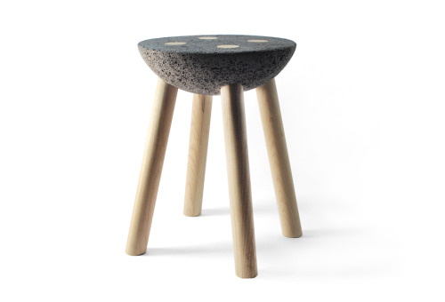 A small stool made of basalt and wooden legs with a basic construction, looking after a clear expres