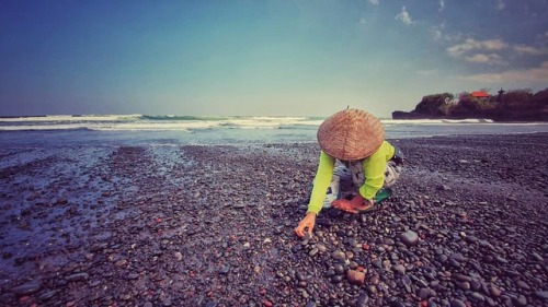 Local women and men collecting small pebbles along the black...