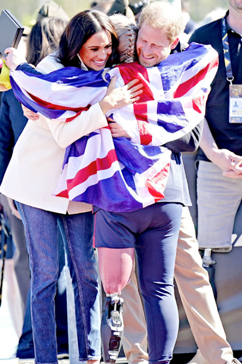 The Duke and Duchess of Sussex hug Lisa Johnston of Team United Kingdom at the Athletics Competition