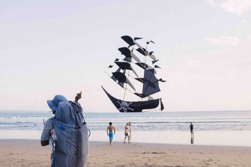 sixpenceee:    Seen here is a perfectly timed/aligned photo of a vendor flying a pirate ship kite that he made. The photo was taken in Seminyak, which is located on the west coast of Bali.   Photograph by bijoubear on reddit.