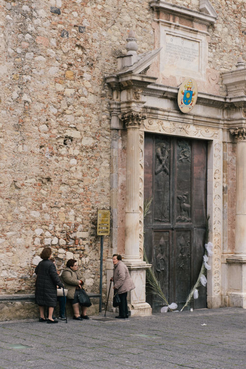A group of women wait outside a church in Taormina, Sicily.