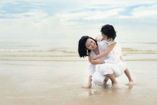 Happy Asian family mother and child daughter hug and play at bea