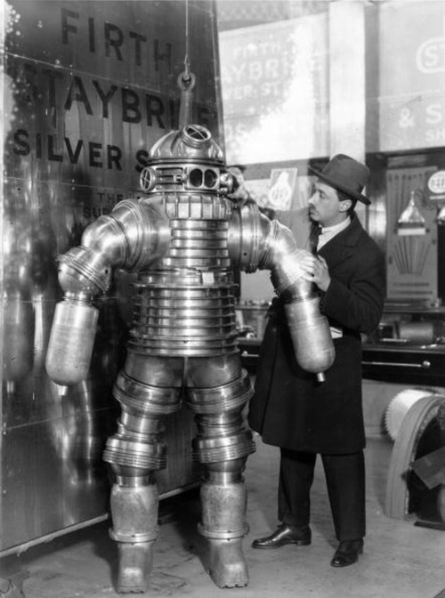 E. Bacon - Inventor J. S. Peress explains the workings of his new rustless diving suit, made of Staybrite Silver Steel, at the Olympia Shipping Exhibition in London. The suit weighs 550 pounds and can work at a depth of 650 feet. 30th November 1925.