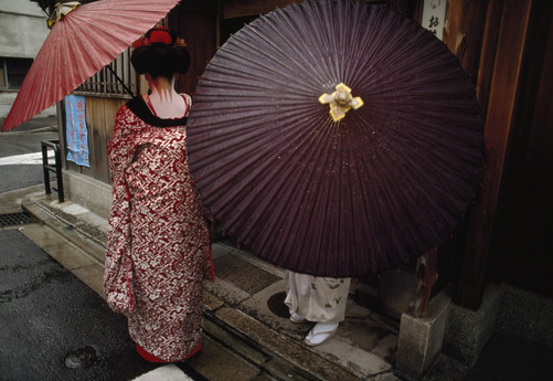 unrar:  Maikos carrying red wax paper umbrellas outside a geisha hous, Japan, Jodi