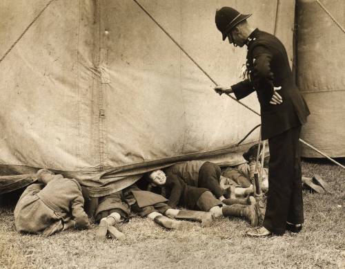 A policeman catches a group of boys sneaking a look at the rehearsals of the Bertram Mills Circus in