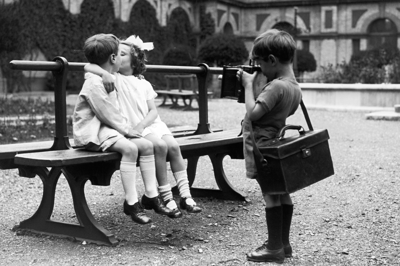 elle-il-eux:  A young photographer capturing a kiss on camera at a children’s party