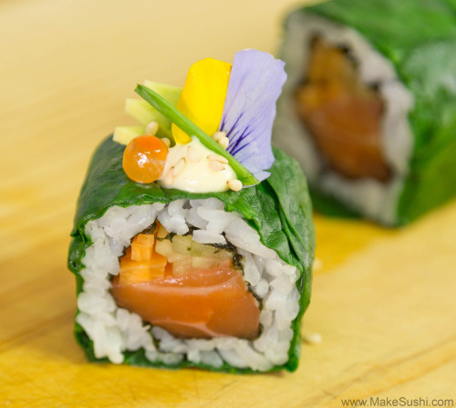 beautiful and elegant sushi roll wrapped in spinach and garnished with kewpie mayo, avocado, chives,