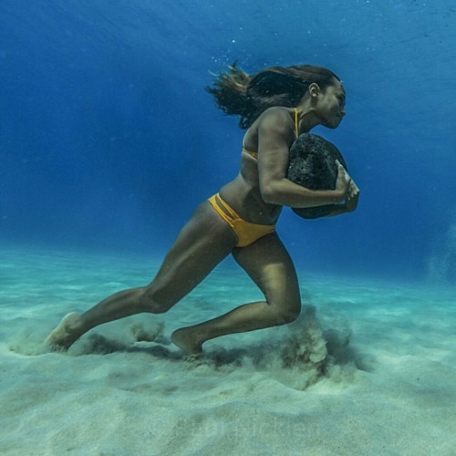 Hawaiian surfer Ha’a Keaulana runs across the ocean floor with a 50 pound boulder, as training to su