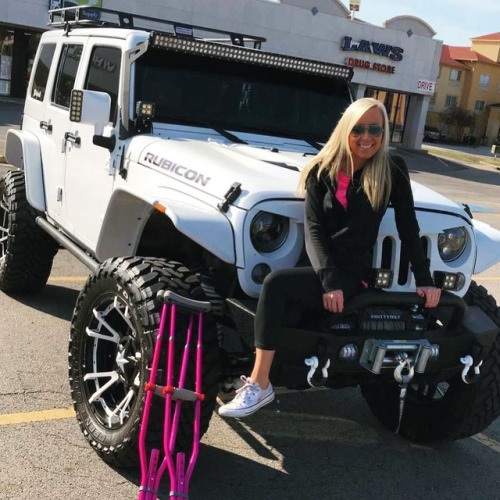 Onelegged girl with white converse shoe, pink crutches is posing on the white car