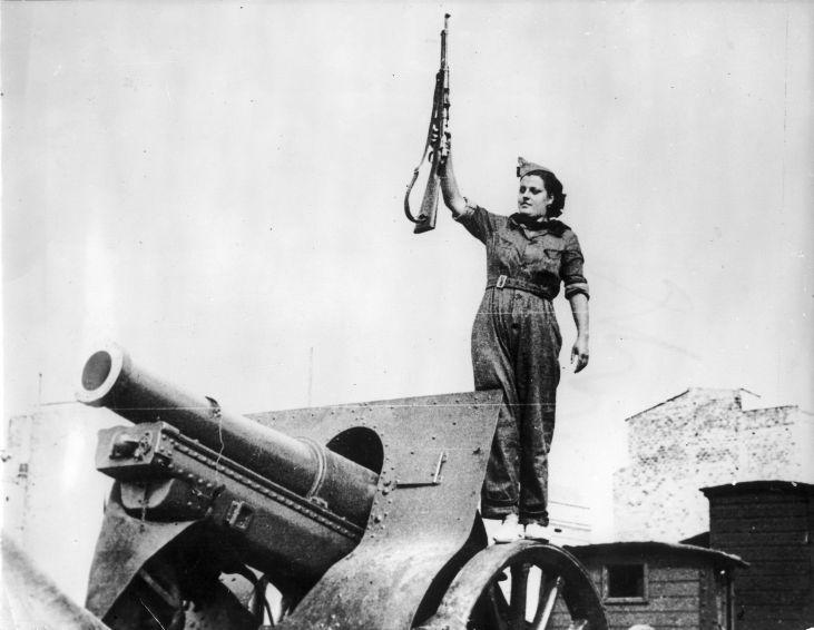 Woman with a rifle standing on a cannon during the Spanish Civil War. Barcelona,