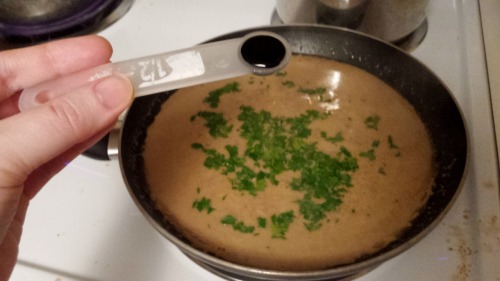 Parsely and kitchen bouquet, an almost-black liquid, being added a frying pan of light brown sauce.