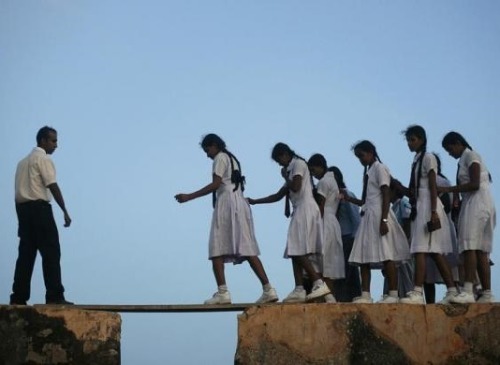 weswegen:School girls walk across a plank on the walls of the 16th century Galle fort, Sri Lanka, Ju