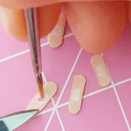 a pink heart shape being drawn on a miniature bandaid