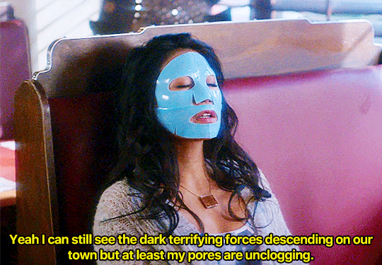 GIF FROM EPISODE 1X07 OF NANCY DREW. VICTORIA SITS IN A BOOTH AT THE CLAW WITH HER HEAD RESTING AGAINST THE BACK OF THE BOOTH. SHE HAS AN AZURE BLUE FACE MASK COVERING HER FACE WITH OPENINGS FOR HER EYES, NOSTRILS, AND MOUTH. HER EYES ARE CLOSED. SHE SAYS "YEAH I CAN STILL SEE THE DARK TERRIFYING FORCES DESCENDING ON OUR TOWN BUT AT LEAST MY PORES ARE UNCLOGGING."