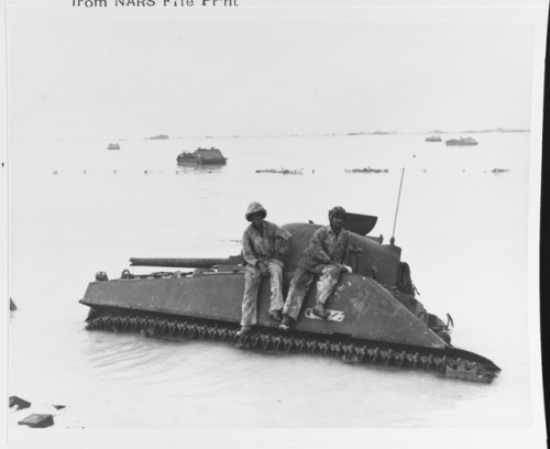 meninroad:Two marines rest on a broken-down M-4 “Sherman” tank, just off one of the Betio Island lan