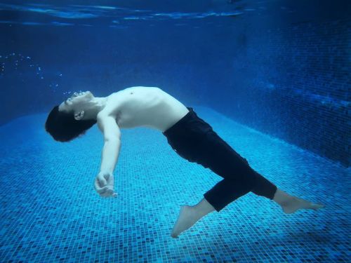 Half clothed barefaced man sinking underwater