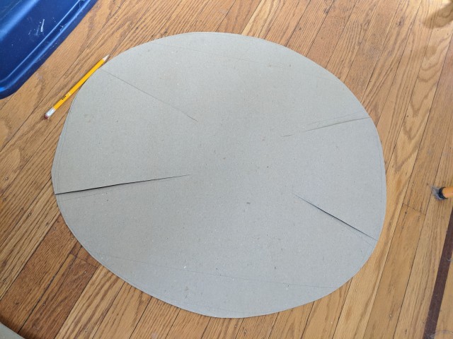 the cardboard sheet cut into a circle with four slits cut into it from the edge, pointing to the center