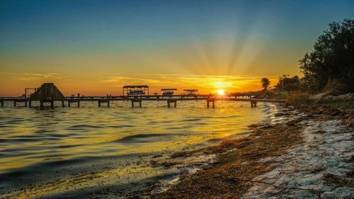 Sunset At The Dock by Stuart Schaefer Photography It was a bright sun at Oriole Beach in Gulf Breeze