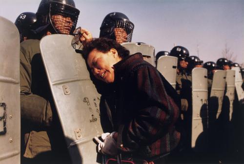 adapto: Anthony Suau (1988) A mother clings to a riot policeman’s shield at a polling station.