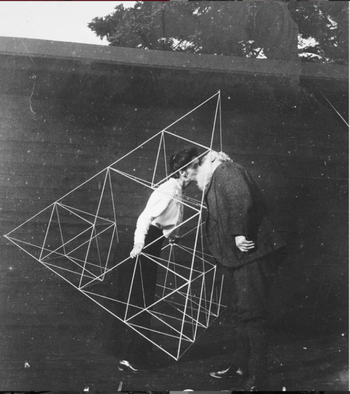 Alexander Graham Bell kissing his wife, Mabel, who stands inside one of his spectacular tetrahedron 