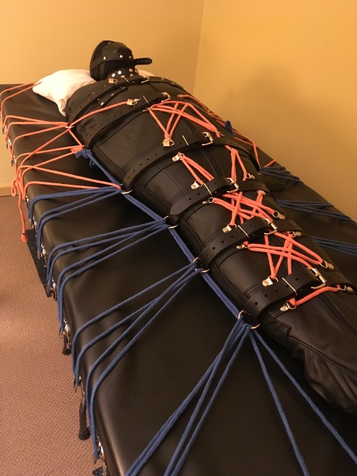 wired4funspike:Anti-Coronavirus-Boredom treatment #122: My NYC friend is back in his leather sleepsack with a muzzle over his hood. In these photos from January 2019, after he is belted in tightly, I first roped him to the bondage table then added at