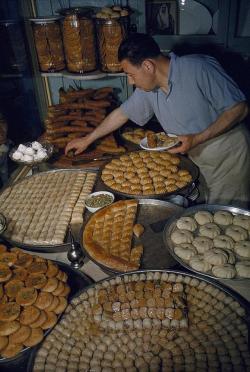 hhigh-priestess:thelostvintage:A man samples baklava and other honey pastries at a bakery, Damascus, Syria   