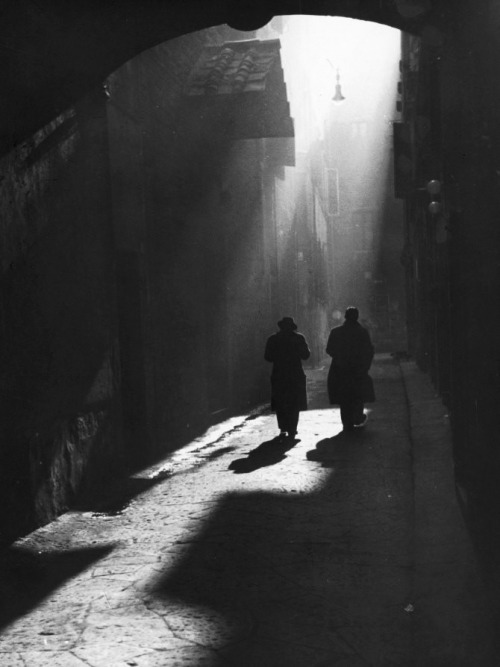 undr: Vincenzo Balocchi. Two men walk on a little street in Florence, 1960