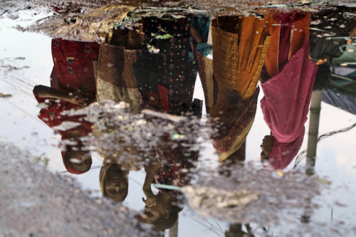 Bangladeshi garment factory workers are reflected on a puddle during a protest in Dhaka on Sept. 23,